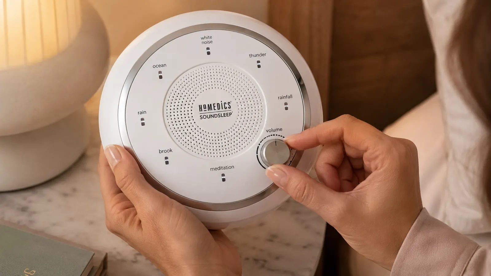 Close-up of the Homedics SoundSleep sound machine showing its six sound selector dial and the silver plastic housing under bright light
